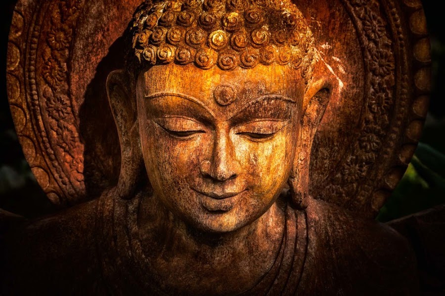 Golden sunset light caresses a wooden buddha statue in Chennai, India.